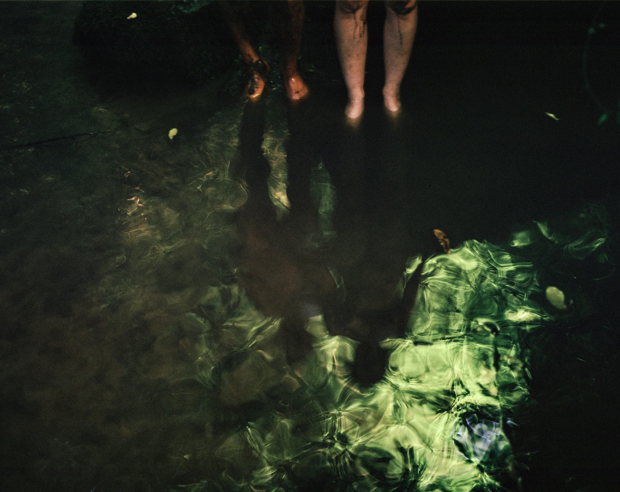 Blurry image showing two pairs of legs standing in greenish water © Cansu Yıldıran