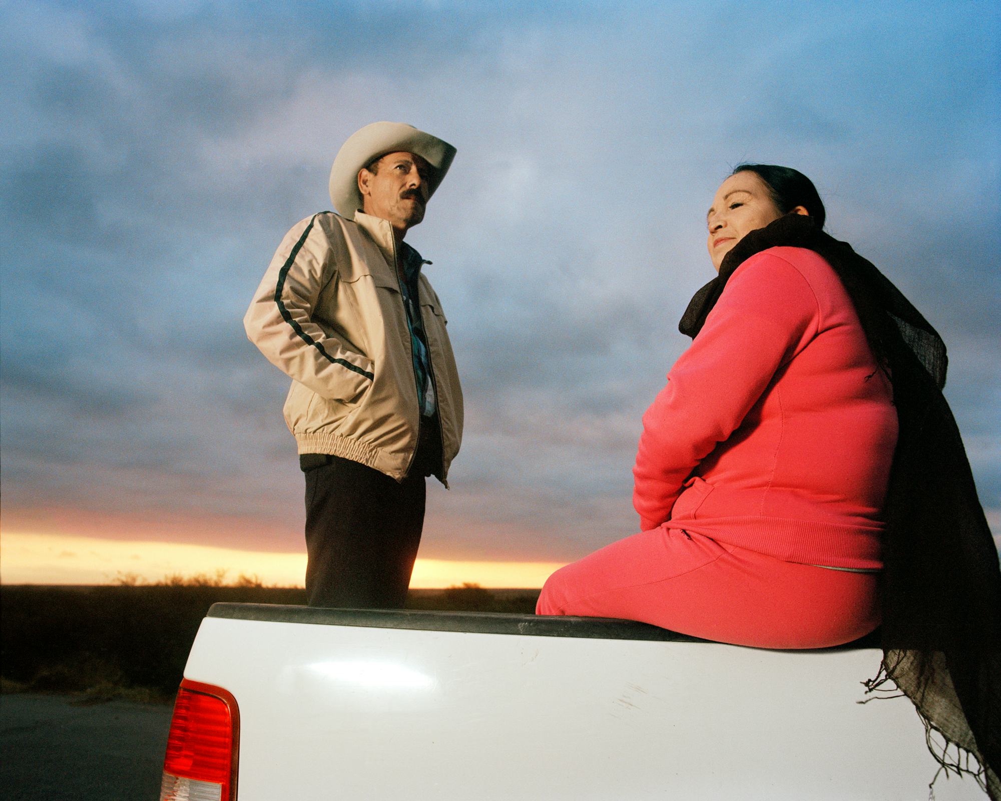 Man standing and woman sitting in the back of a pickup truck