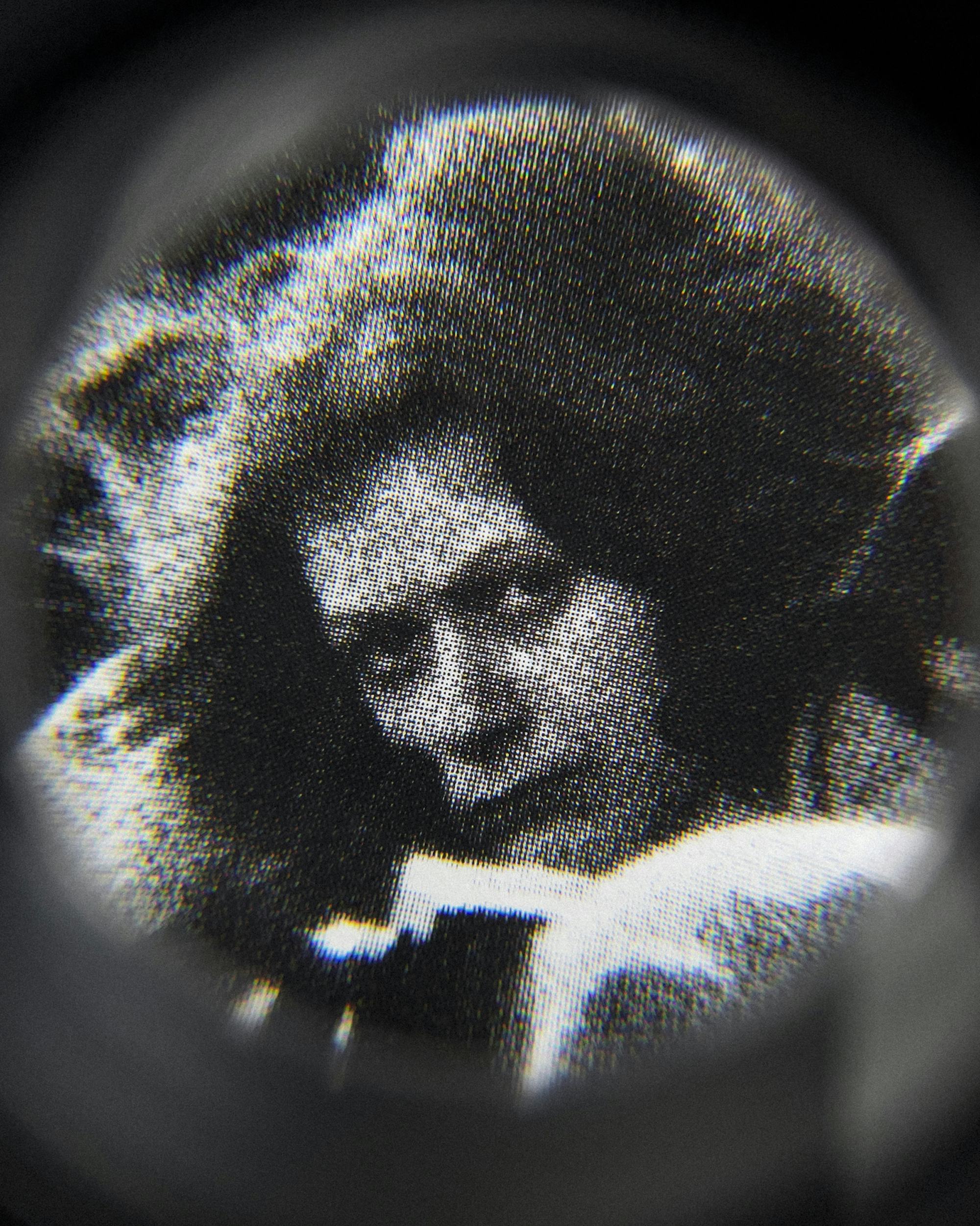 Black and white close-up image of an existing photograph, showing a woman staring into the camera. Shot through a magnifying lens © Amin Yousefi