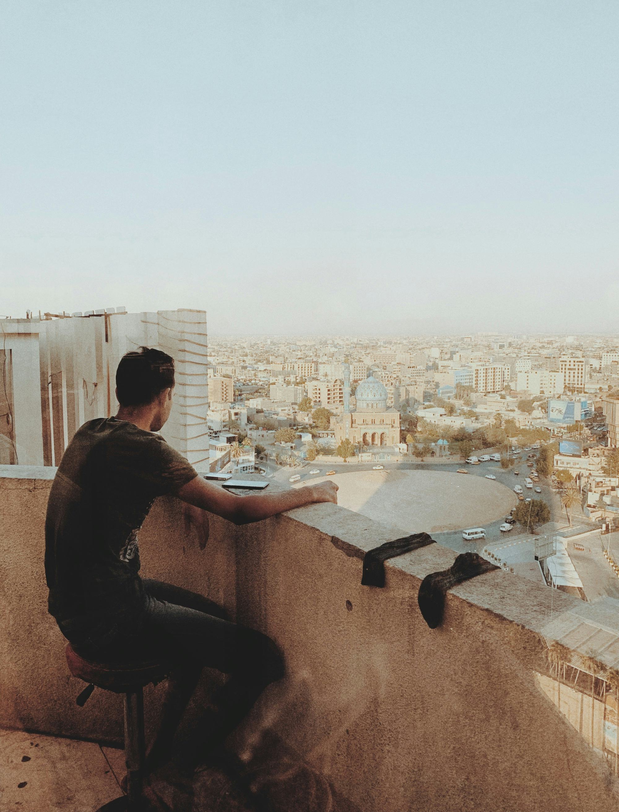 Young man sitting on a balcony, looking of a city in Iraq