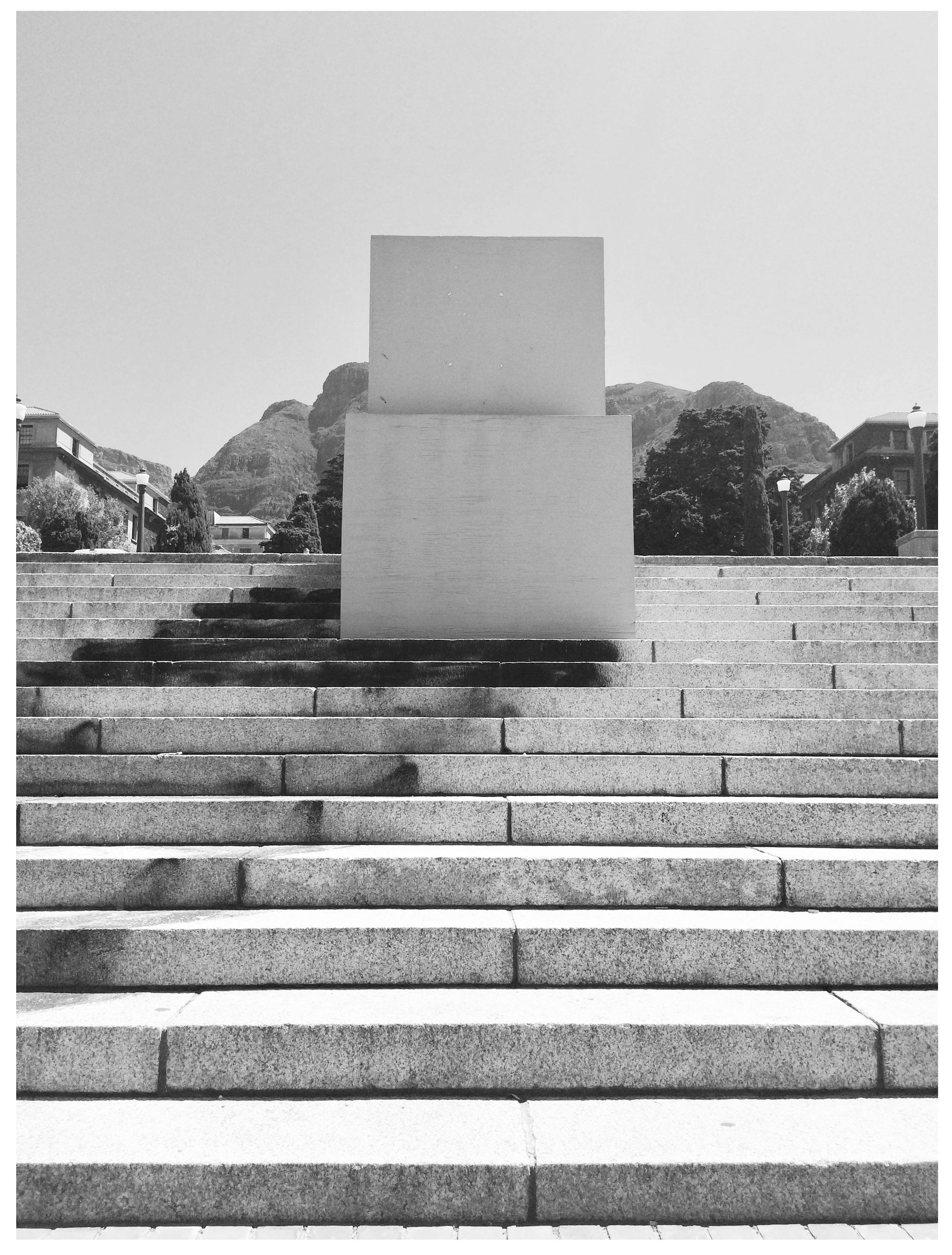 Black and white photo of the empty and boxed-up pedestal where the statue of Rhodes once stood