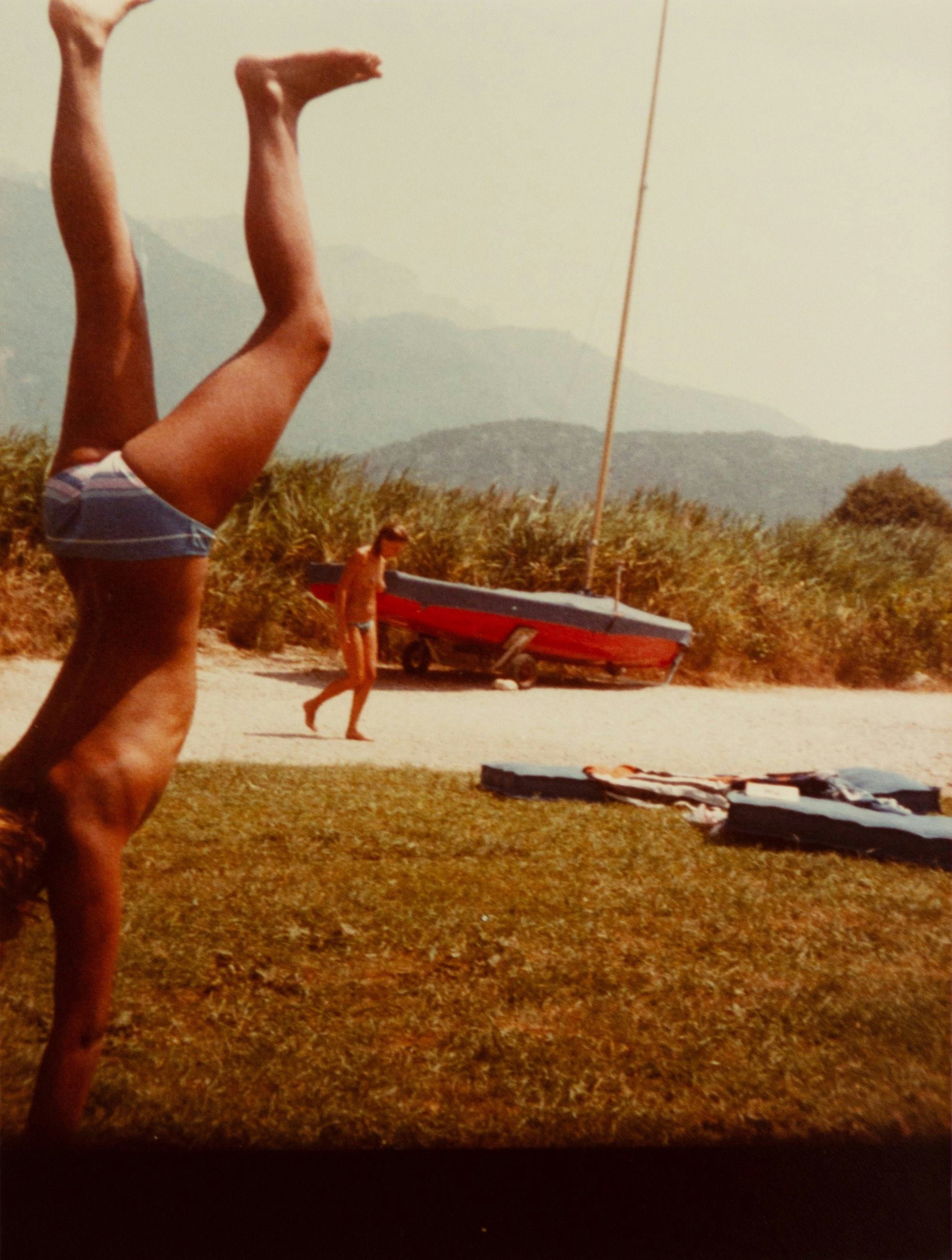 Archival holiday picture from the artist's personal archive, showing a boy in swimming costume standing on his hands© Sander Coers