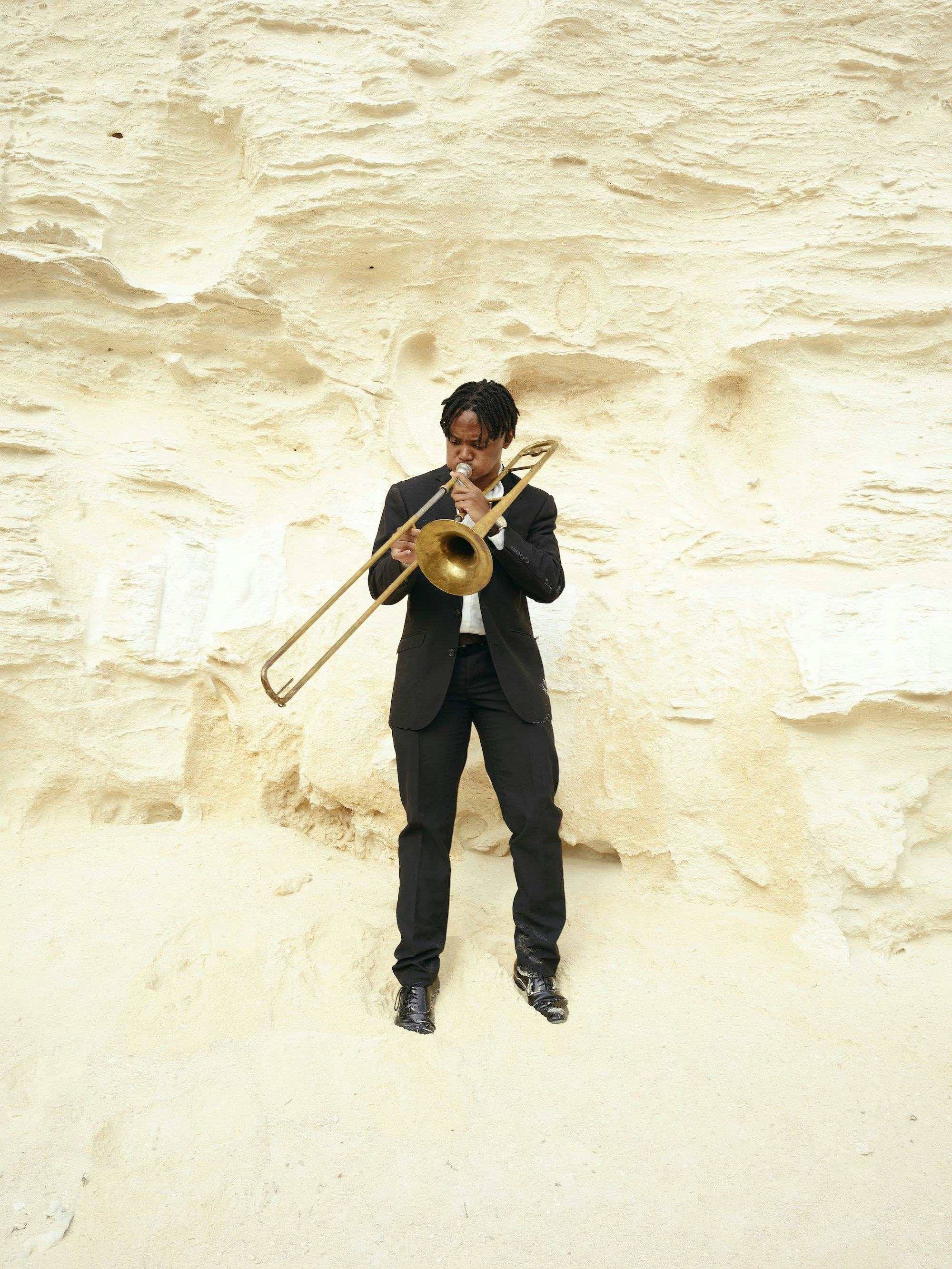 Self portrait of the artist in front of a mountain, playing the trombone © Thero Makepe