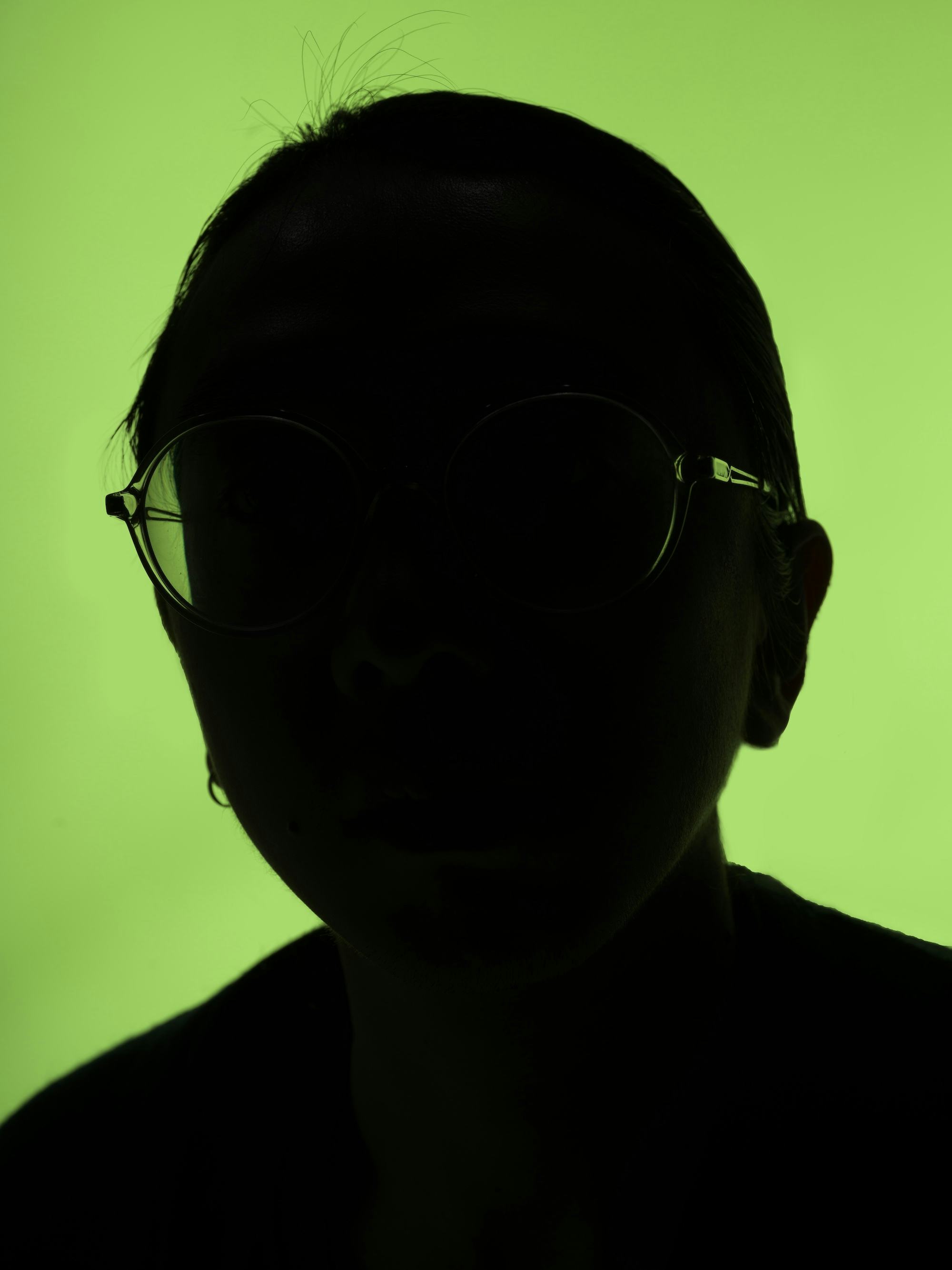 Self portrait of the artist, only showing the outline of the face in front of a green background. © Sheung Yiu