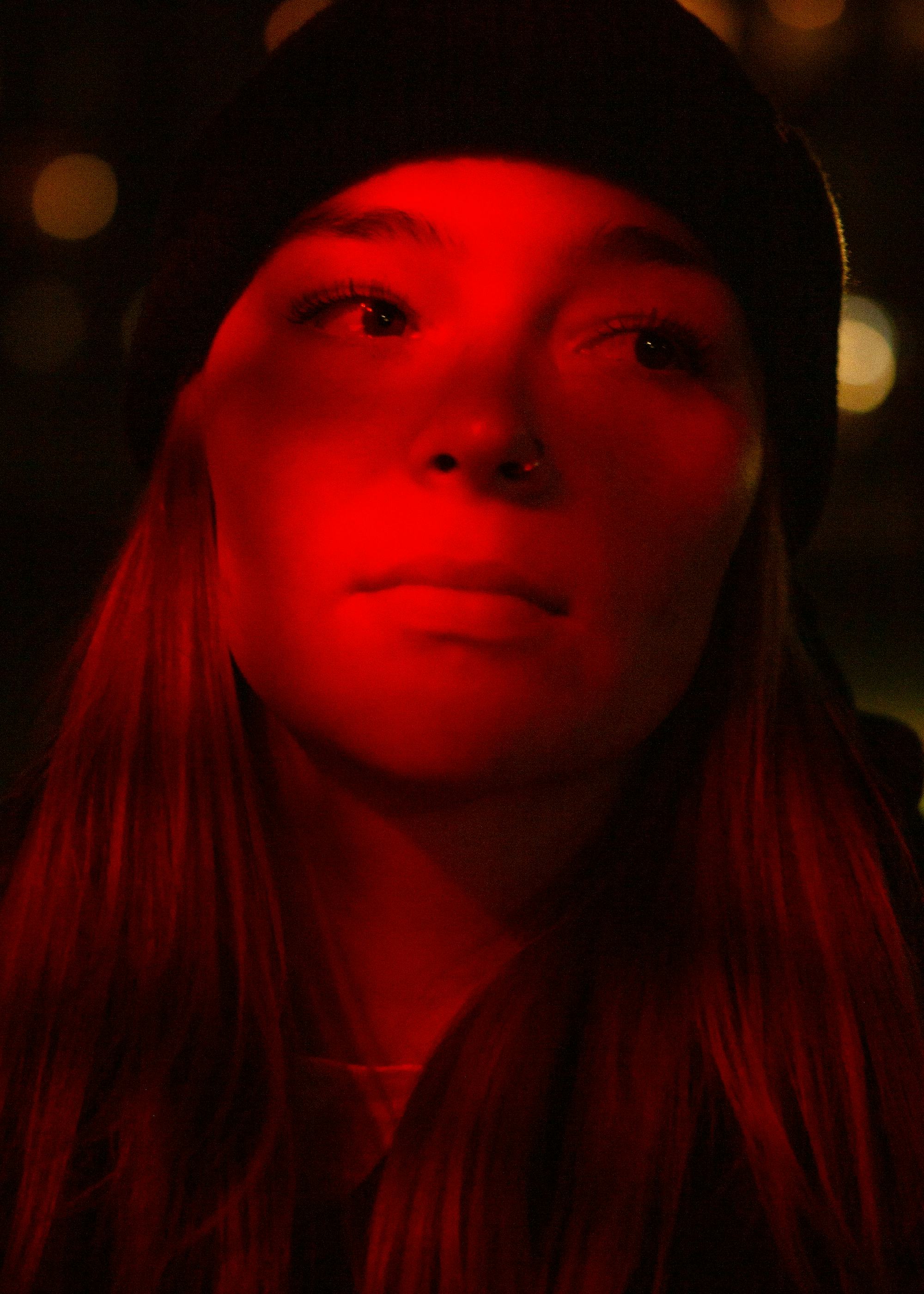 portrait of a person with a red light over them, looking away from the camera