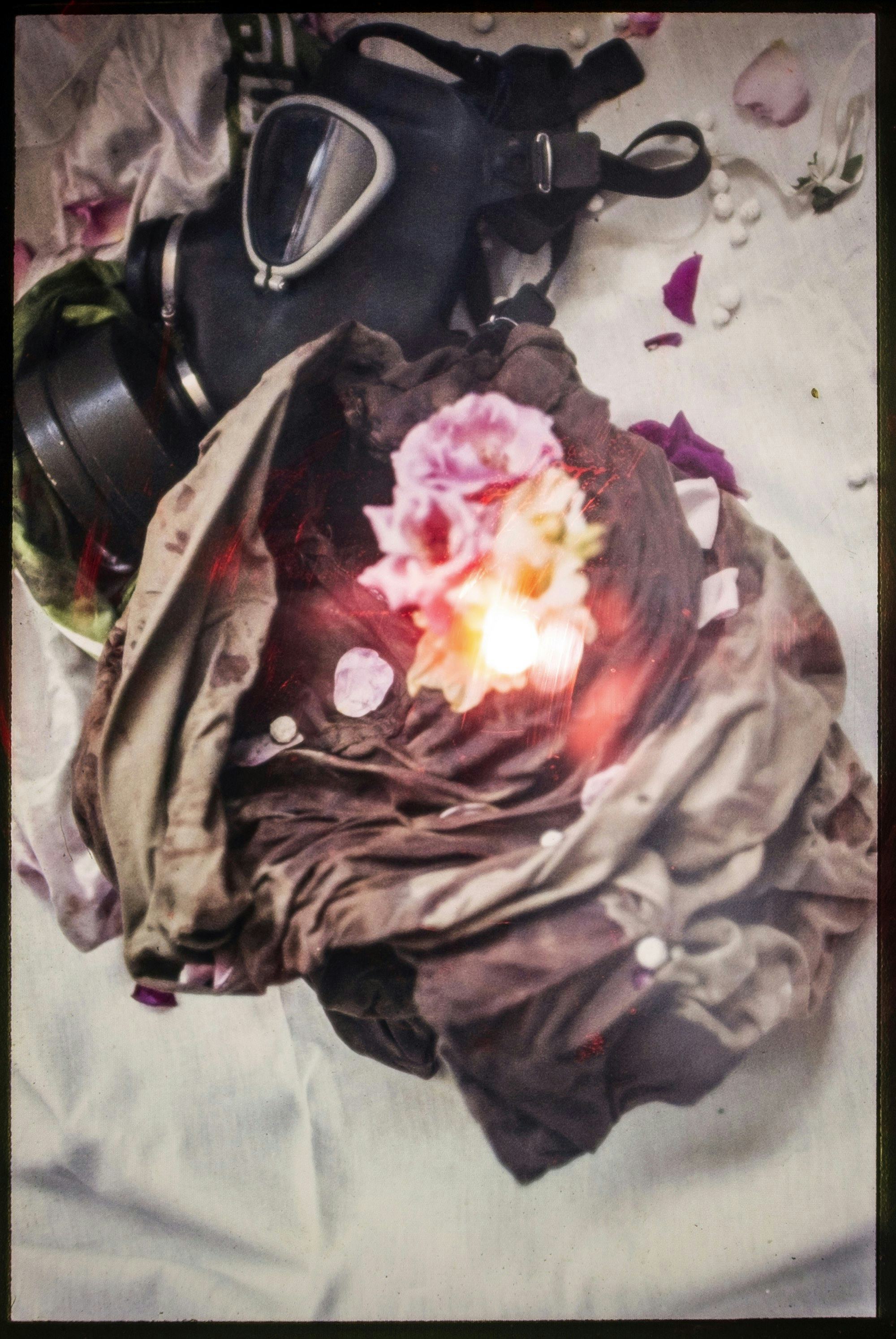 Photograph of a bag with flowers and a gas mask. © Ghazaleh Rezaei