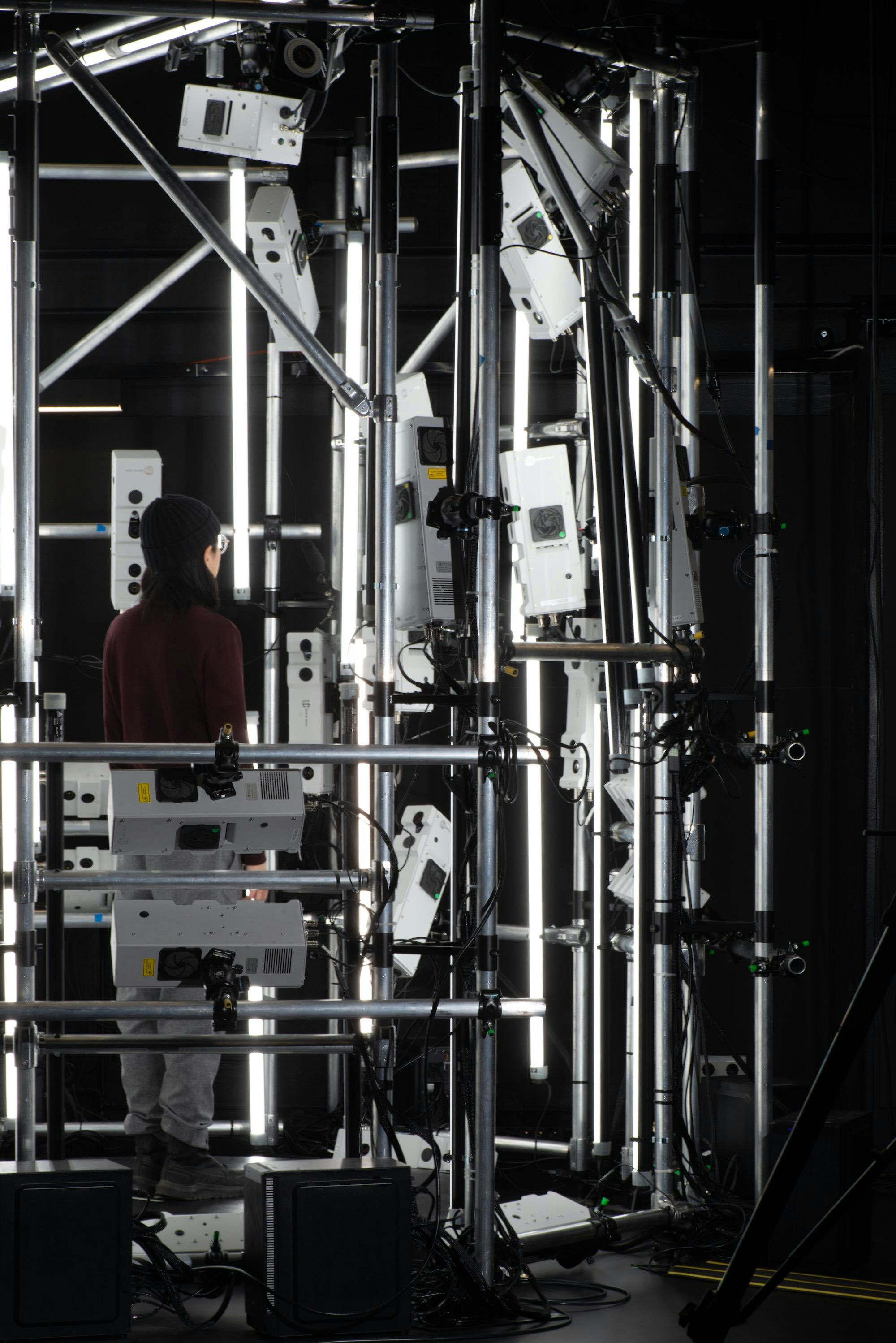 Photograph of a 3D scanning device at CIVIT lab in Tampere University. It shows a steel construction with cameras, with the artist standing on the pedestal in the middle. © Sheung Yiu© Sheung Yiu