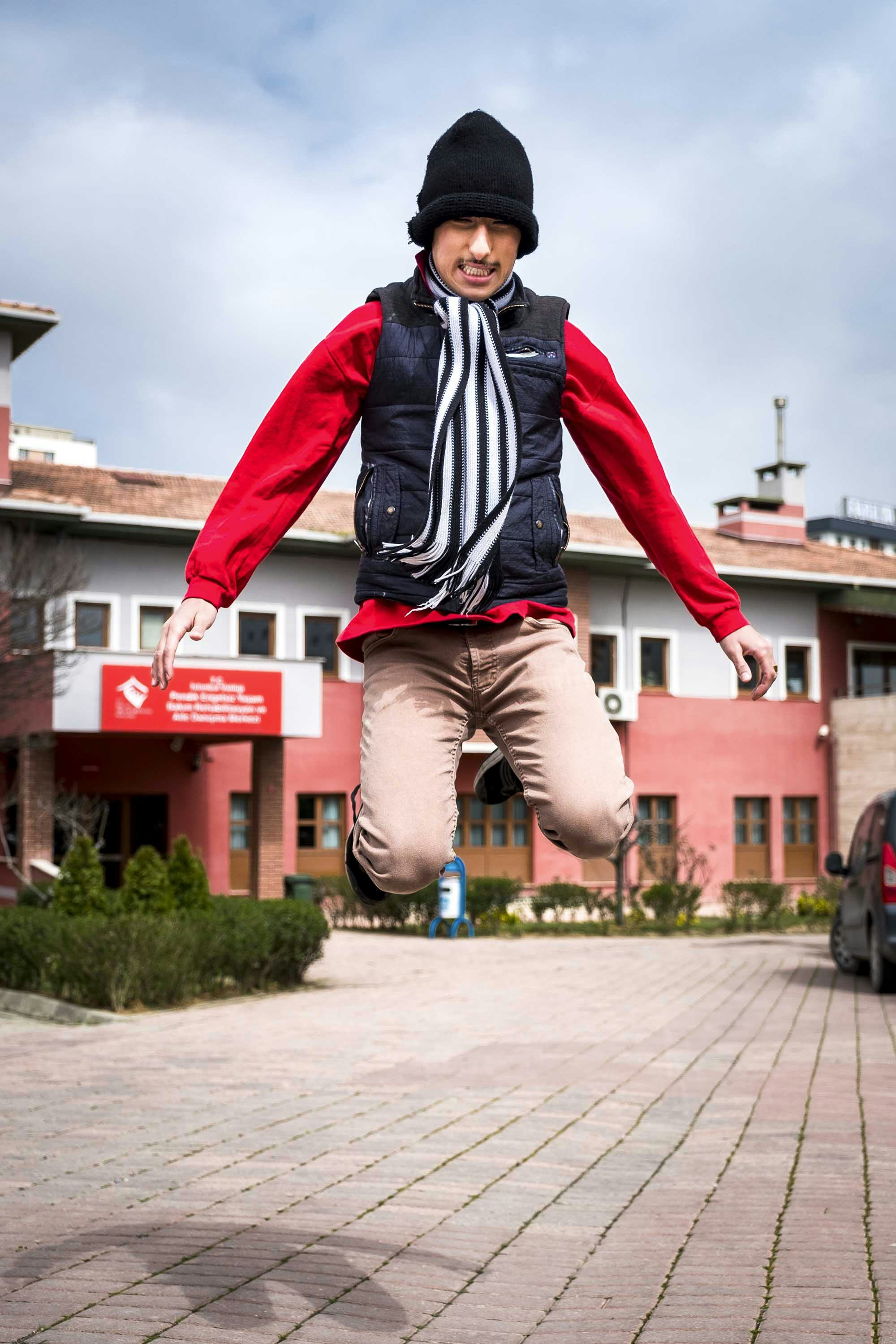A boy wearing a red sweater jumps into the air. © Oğulcan Arslan