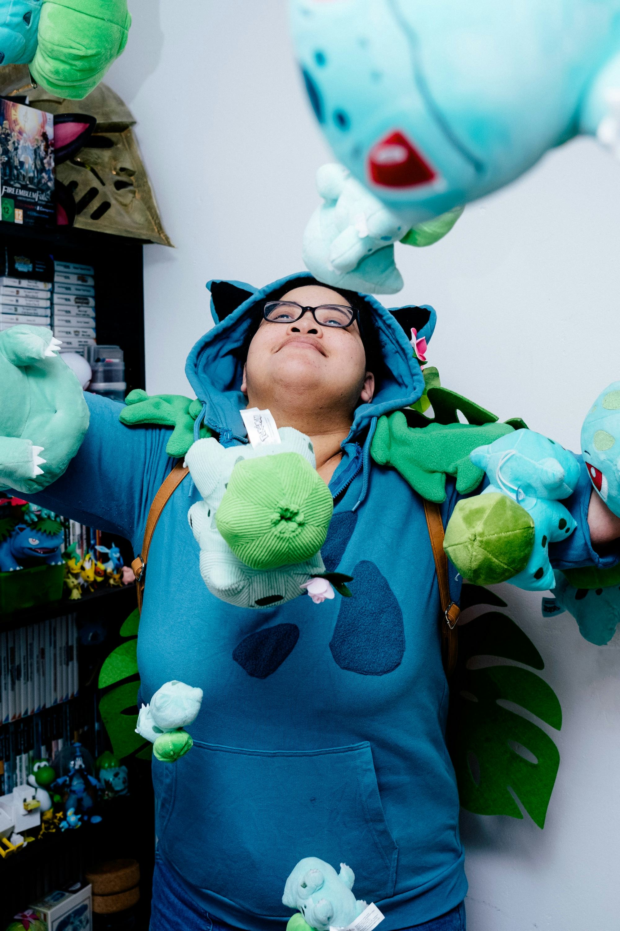 Person with a blue hoodie, throwing a lot of Bulbasaur toys in the air