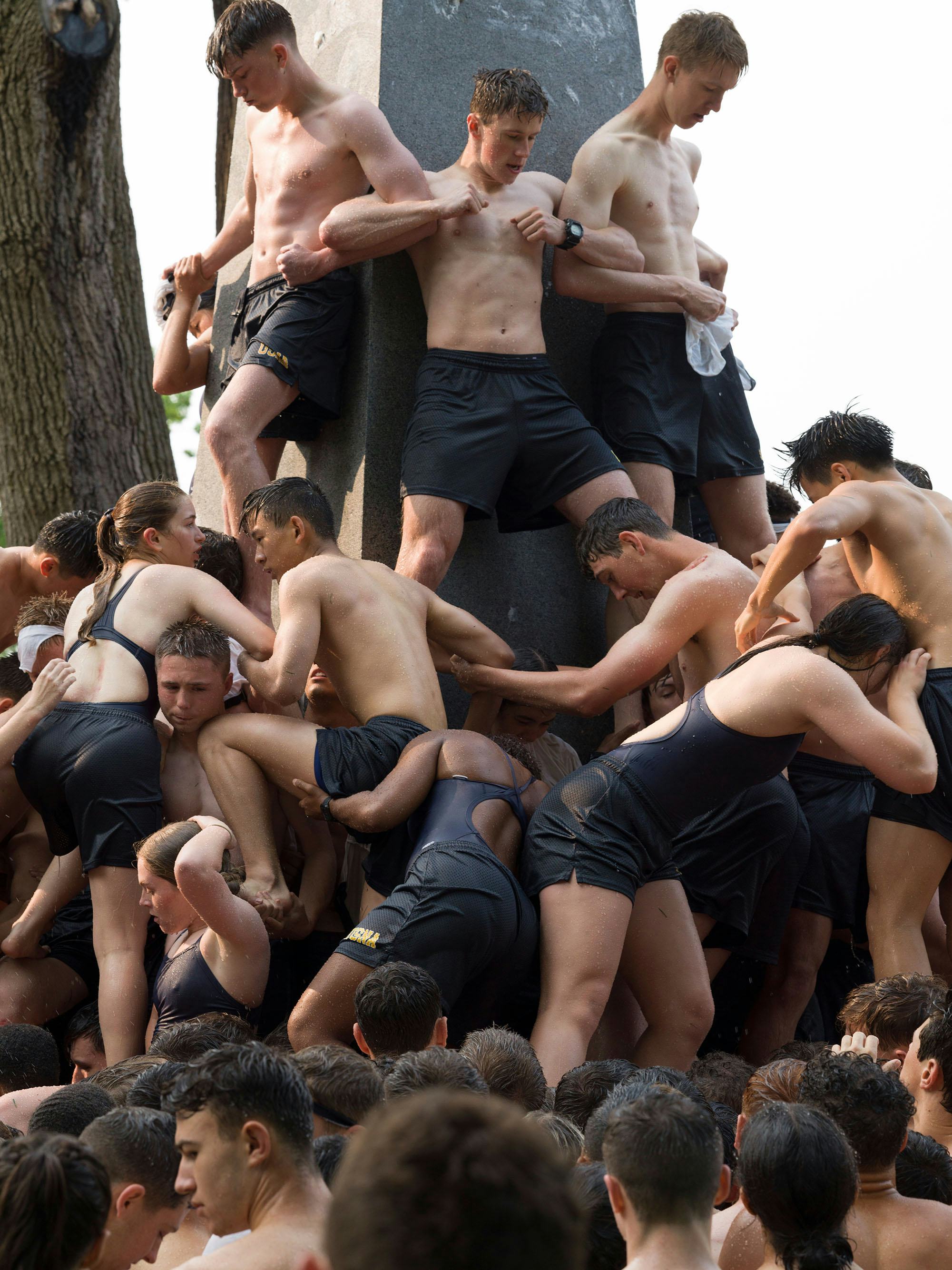 Image of a group of people climbing on top of each other, making a human tower © Andrea Orejarena & Caleb Stein
