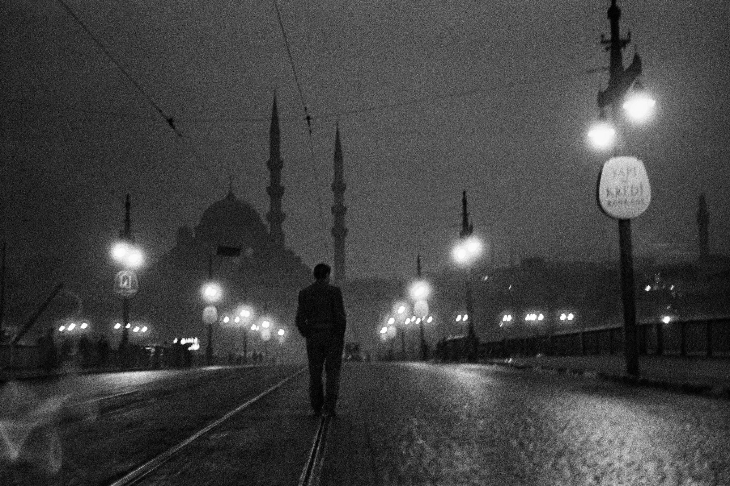 man walkin in instanbul at night with lampposts