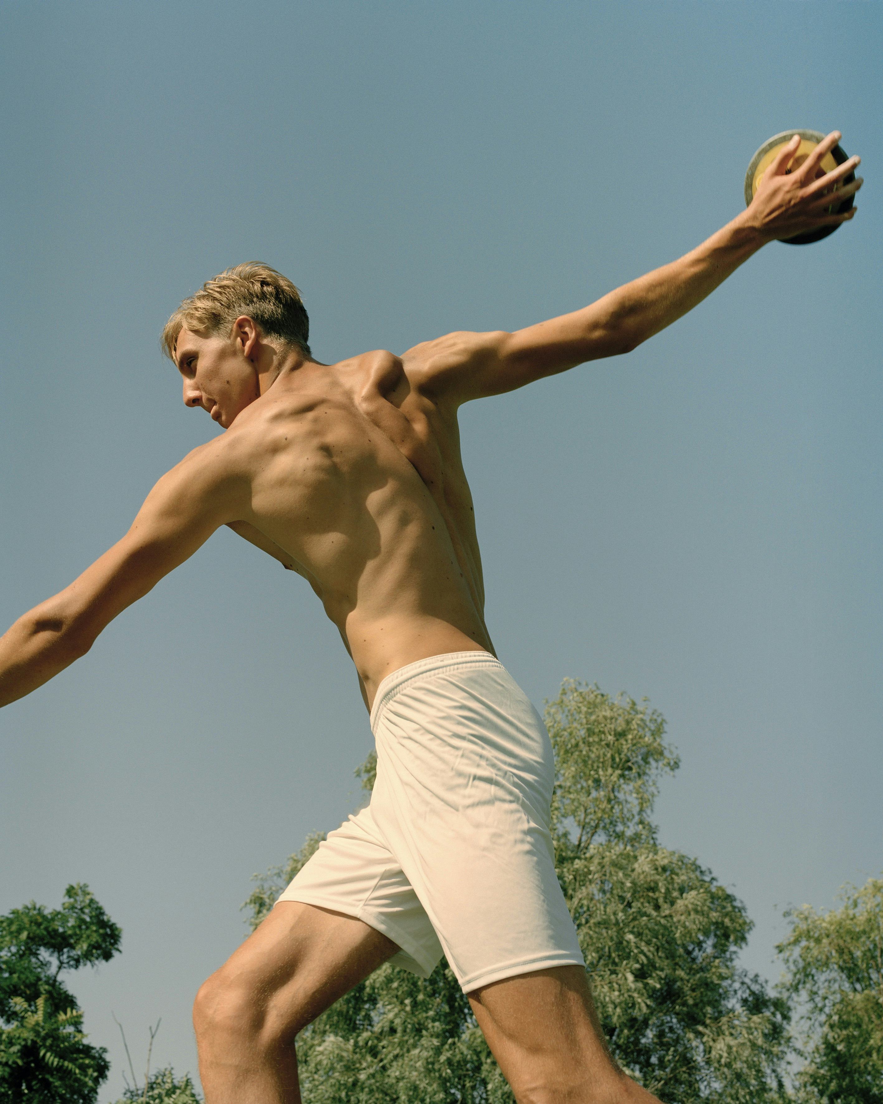Image of a white man in white shorts throwing a disk