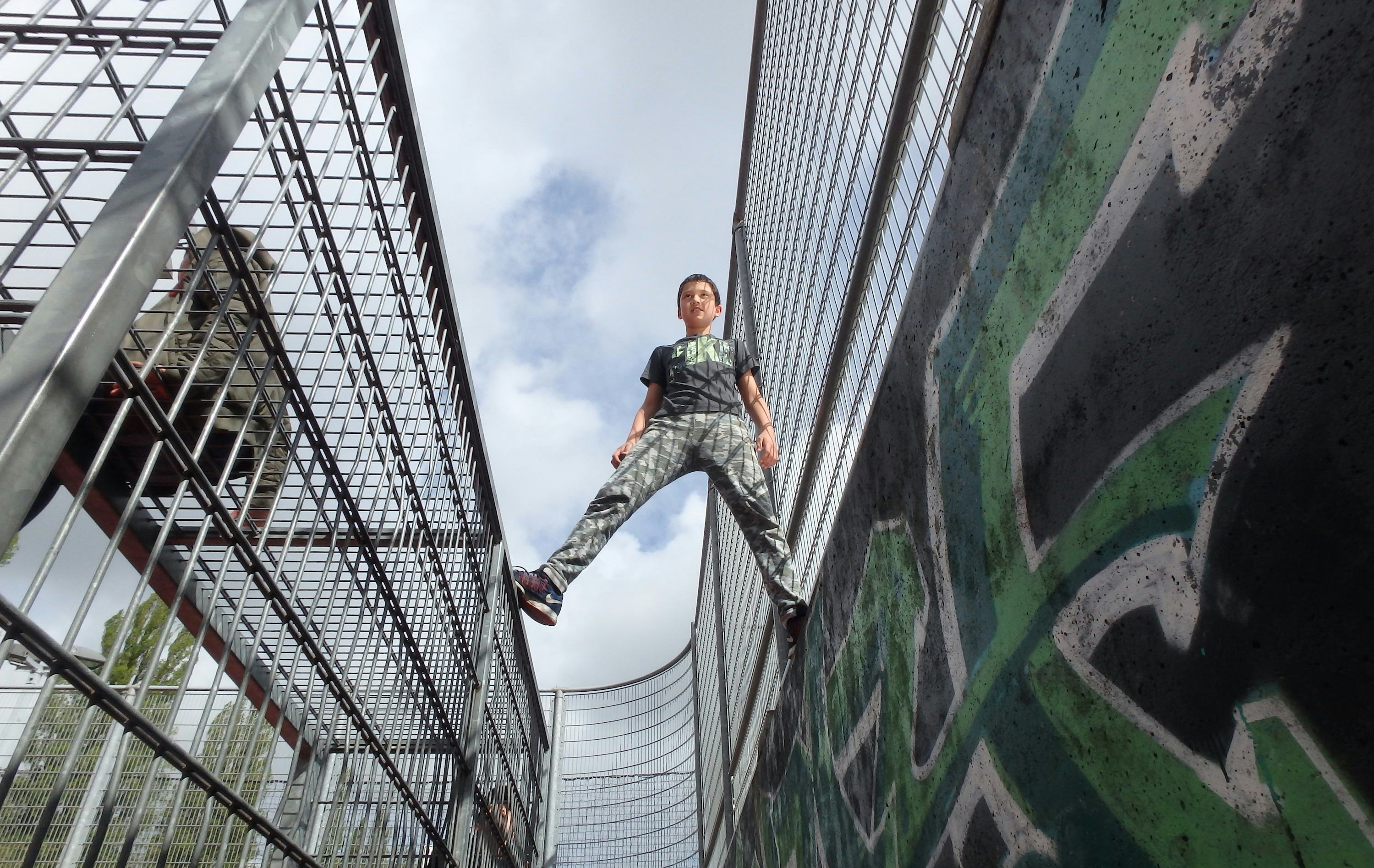 Photo of a boy on top of a graffiti wall and cage construction