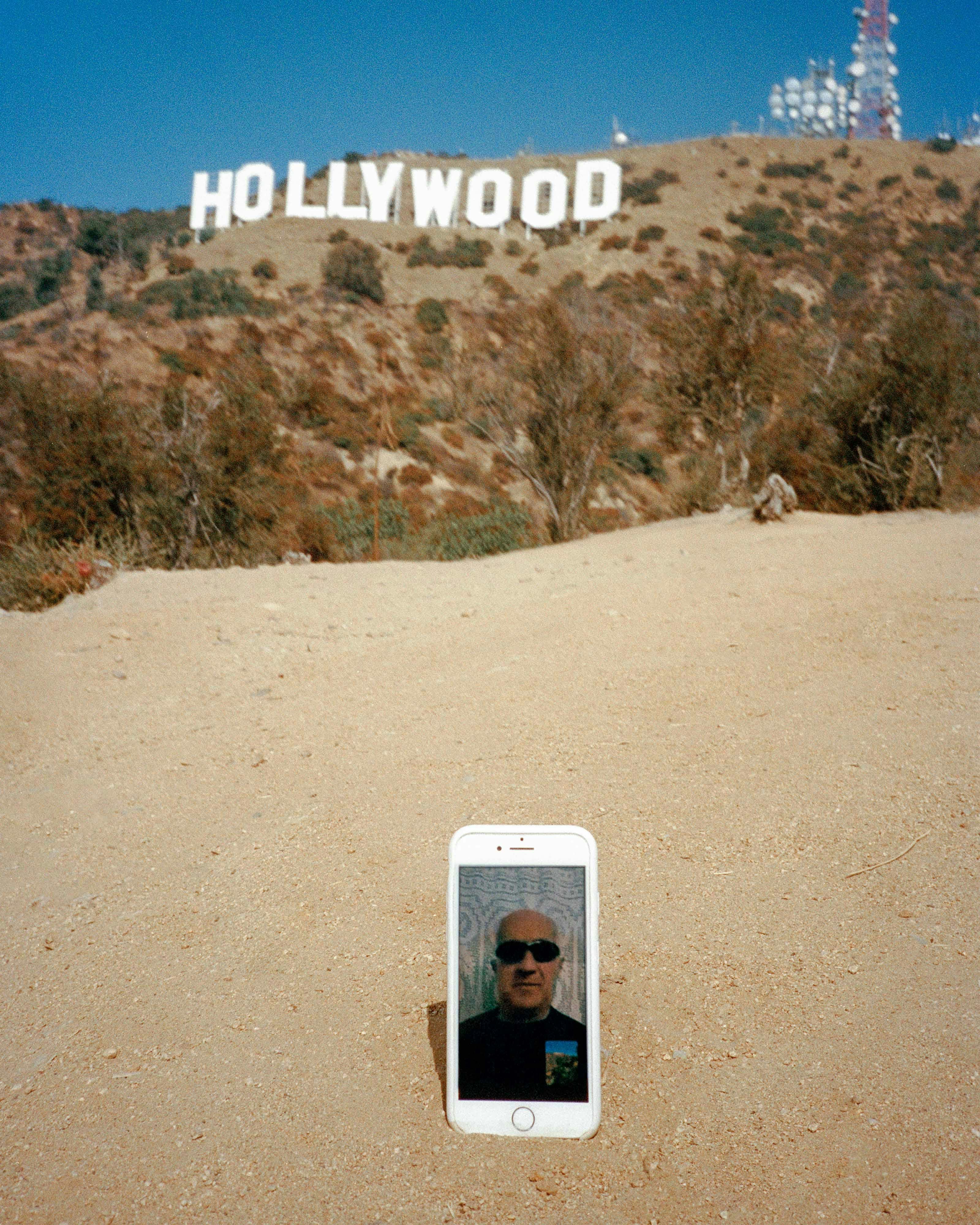 white cellphone in sand with hollywood sign in background