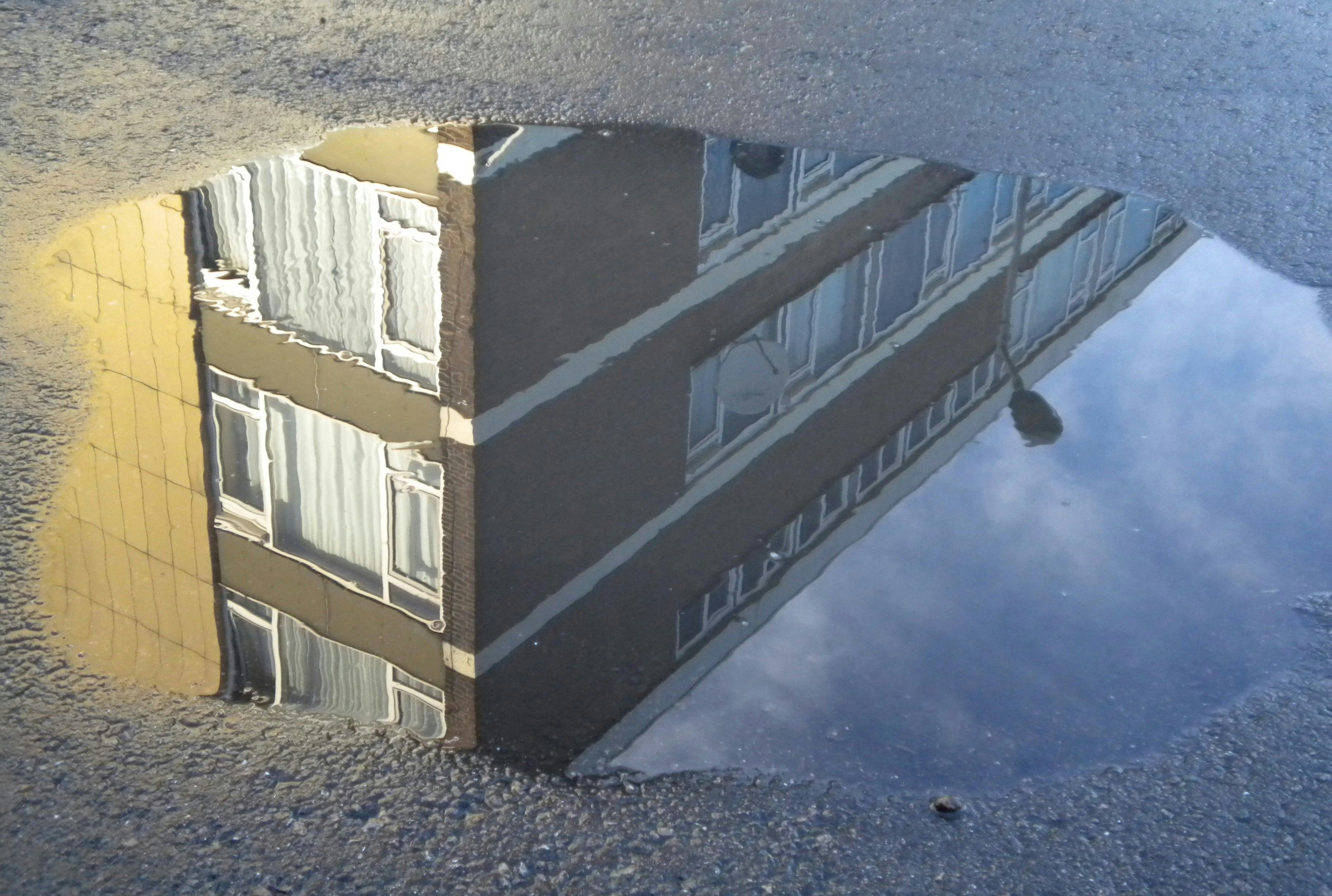 Picture of a water pool on the street, with a building reflected