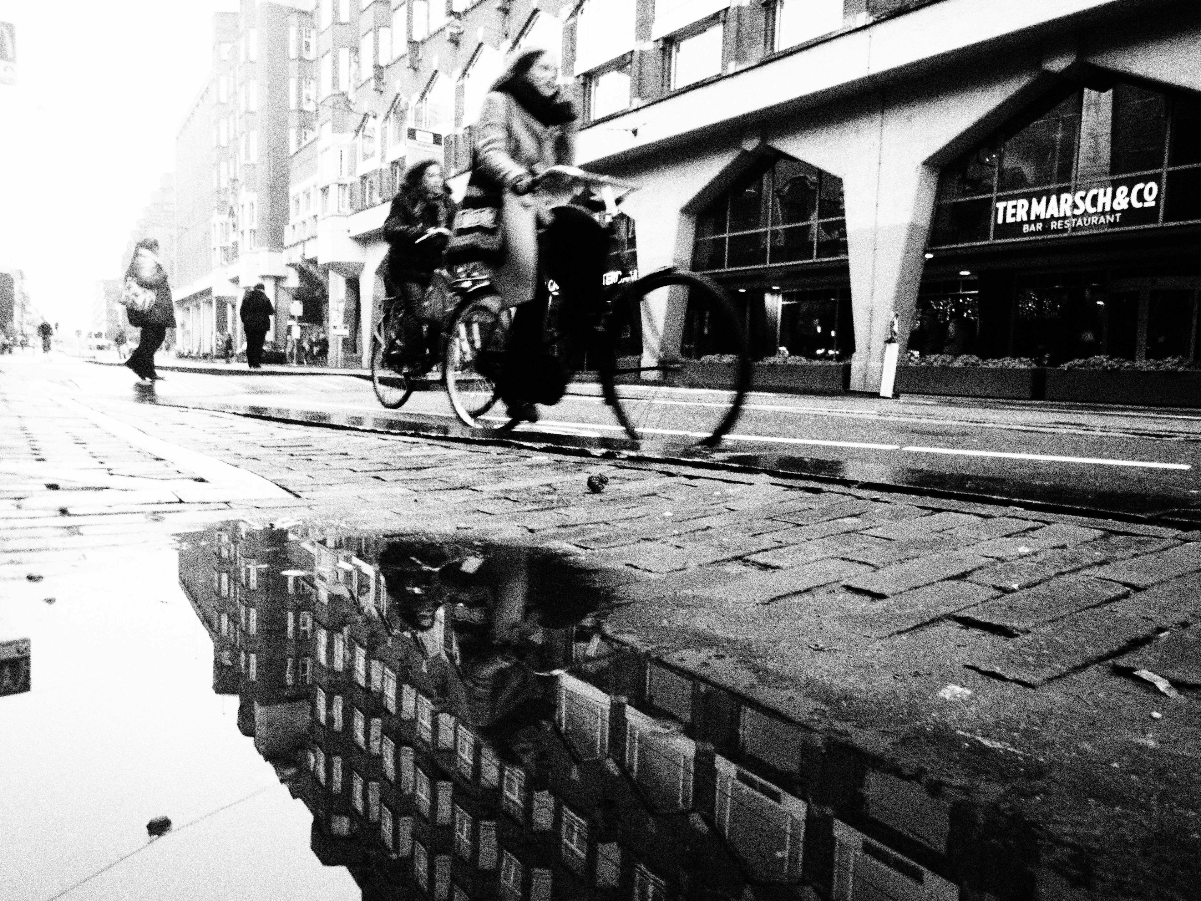 Black and white image of a woman biking in Amsterdam