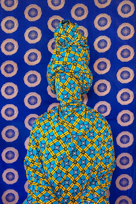 Portrait of a person covered in printed wax fabric. © Alia Ali