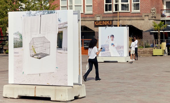Two large scale colour photographs by Vasantha Yogananthan on concrete pedestals on Mercatorplein in Amsterdam.