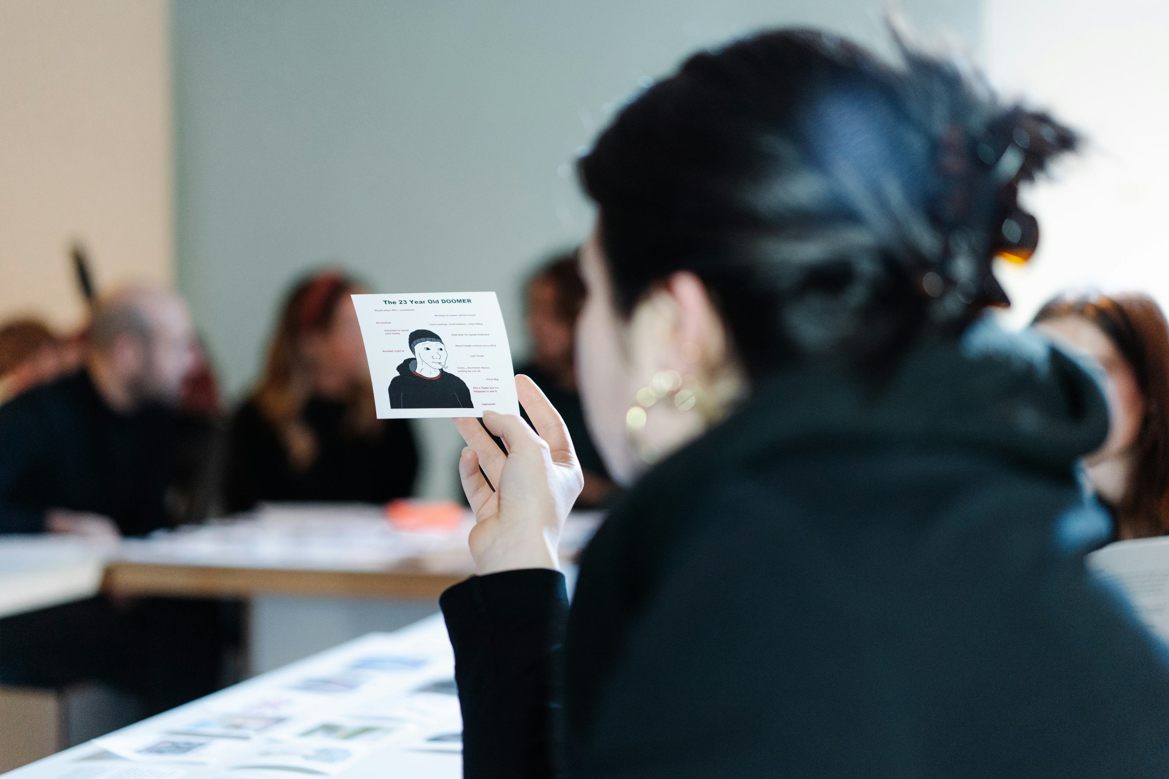 A photo of a girl holding a paper with a popular meme on it during a workshop