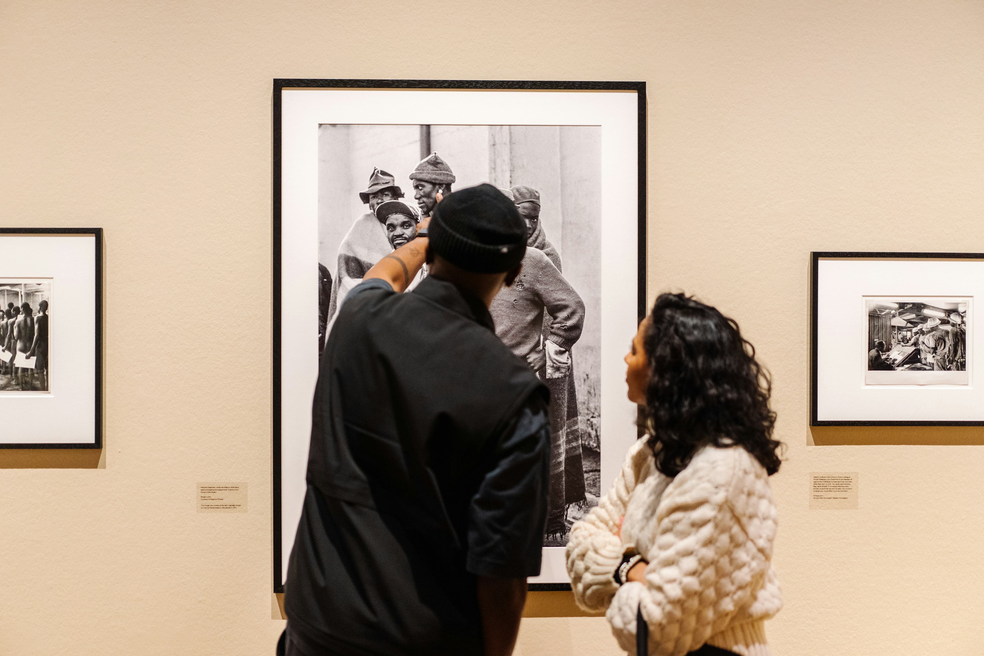Two people looking at a work of Ernest Cole