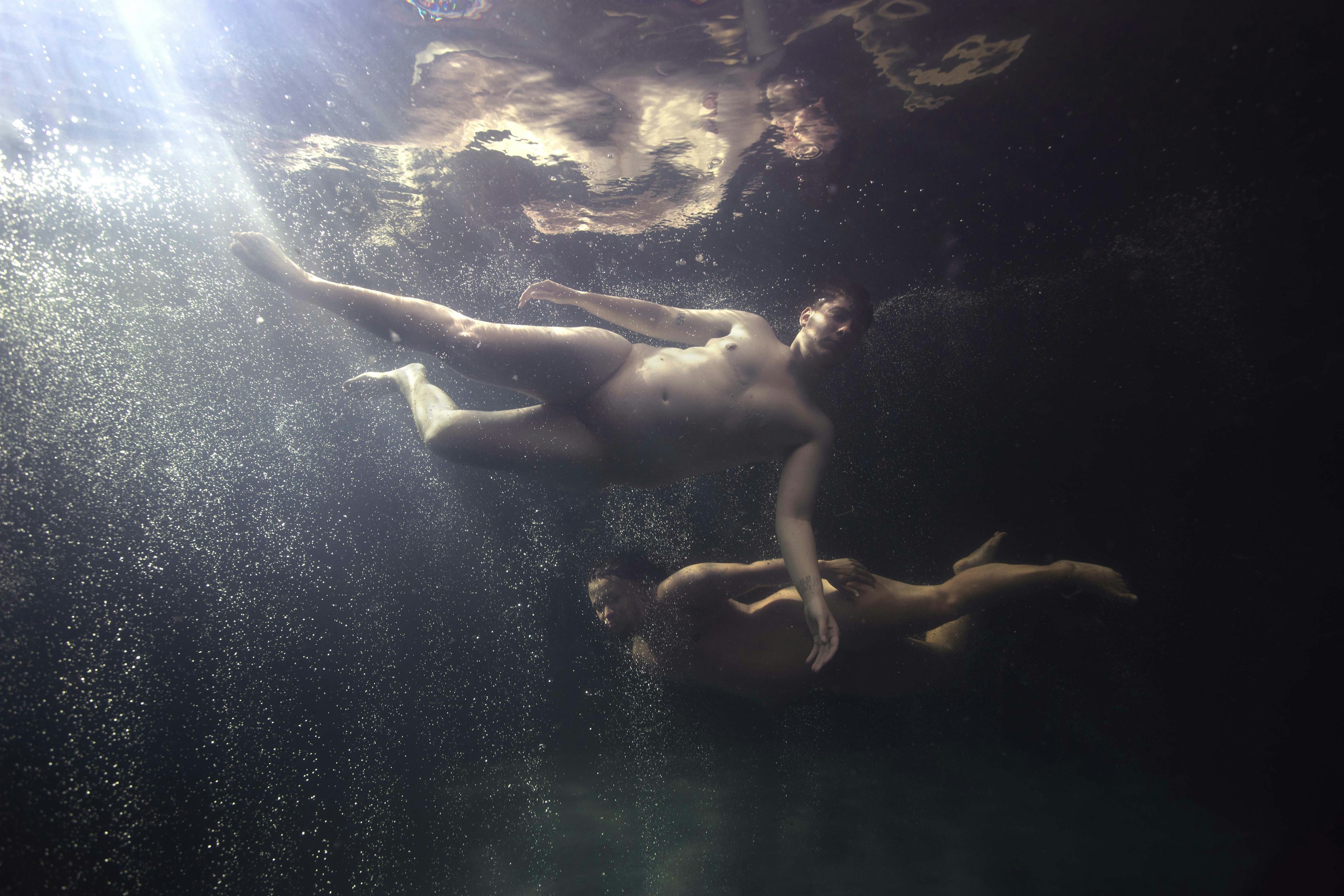 two men swimming light from sun under water