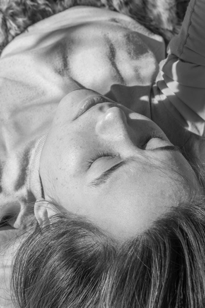 Black and white image of a girl in the sun with closed eyes, taken upside down