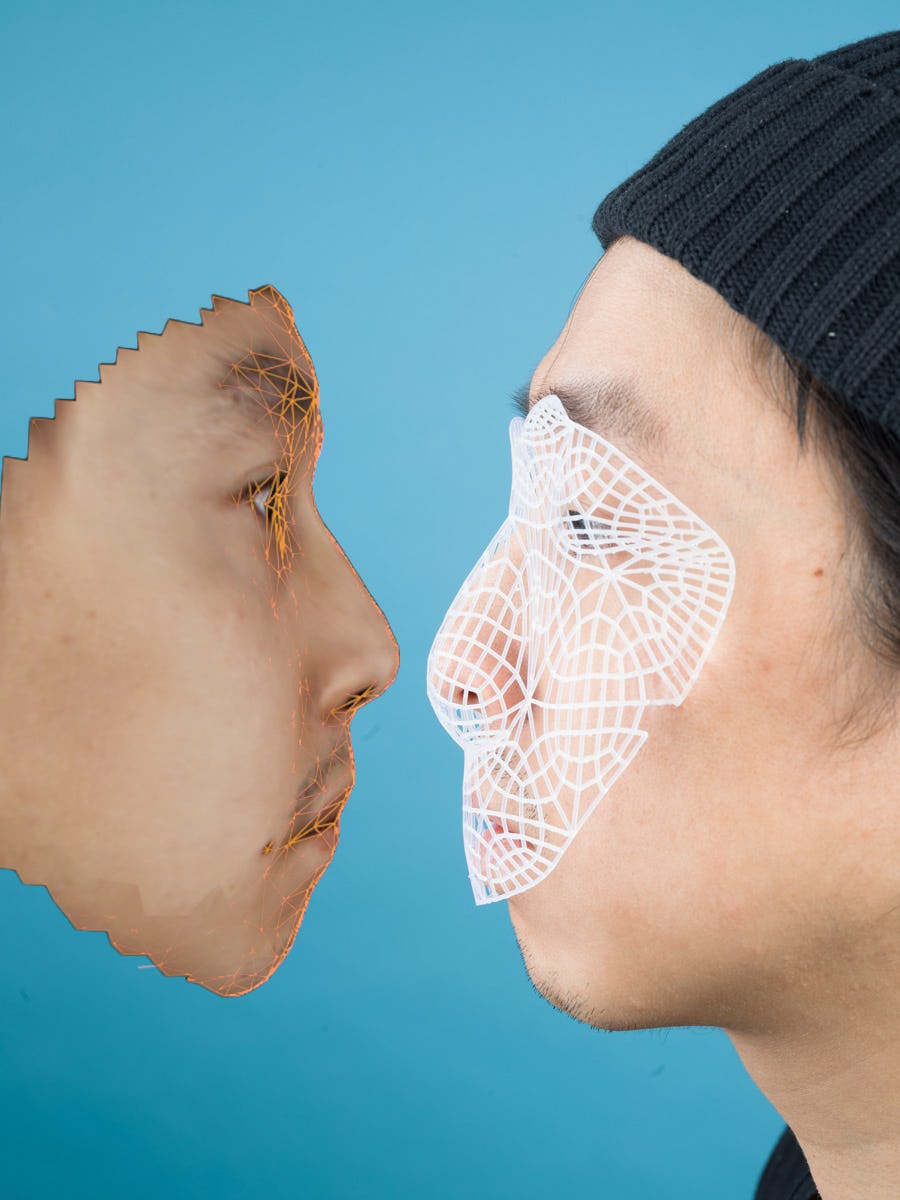 Portrait of the artist's face, in profile, wearing a black hat and a white mesh face mask, facing a 3D scan of his own face© Sheung Yiu